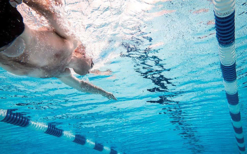 Man with stoma bag swimming in pool colostomy